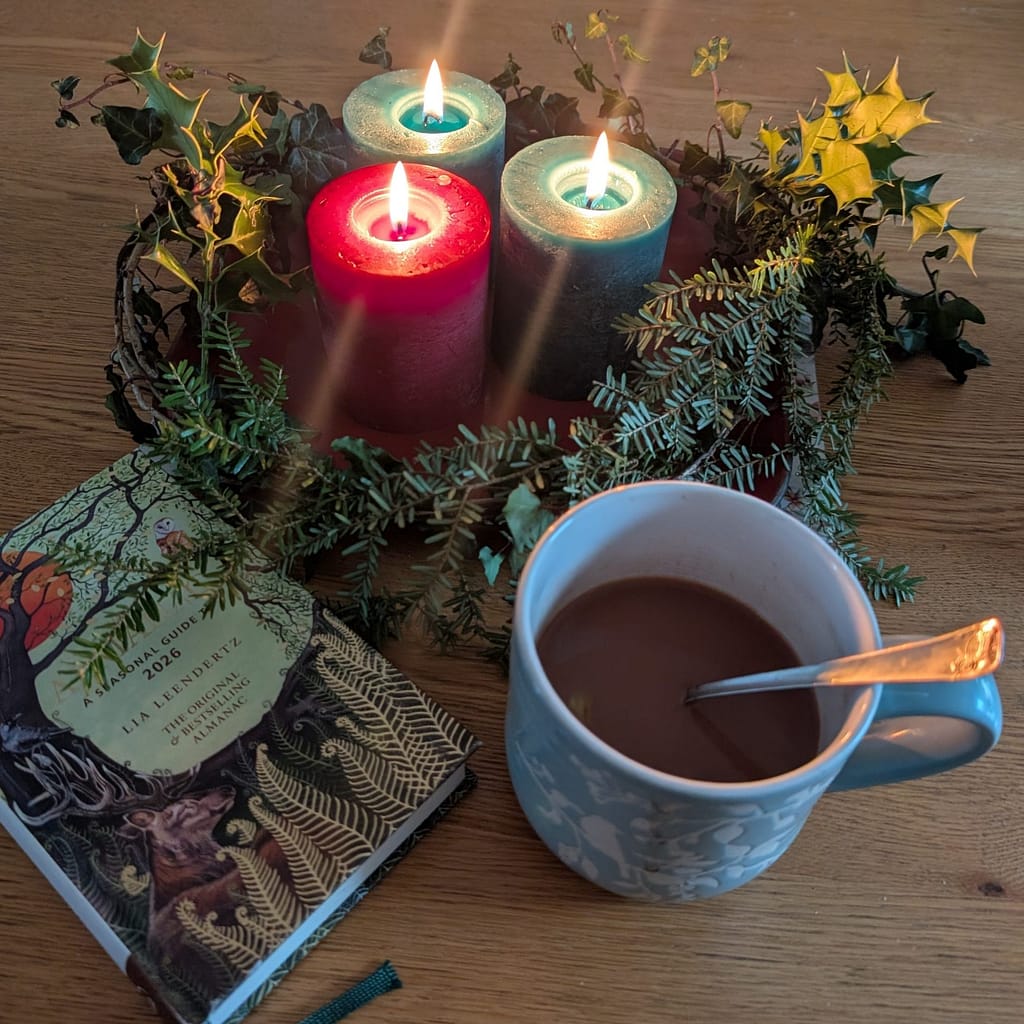 A cosy winter table with candles, hot chocolate and a 2026 almanac, showing why New Year’s resolutions are rubbish in January