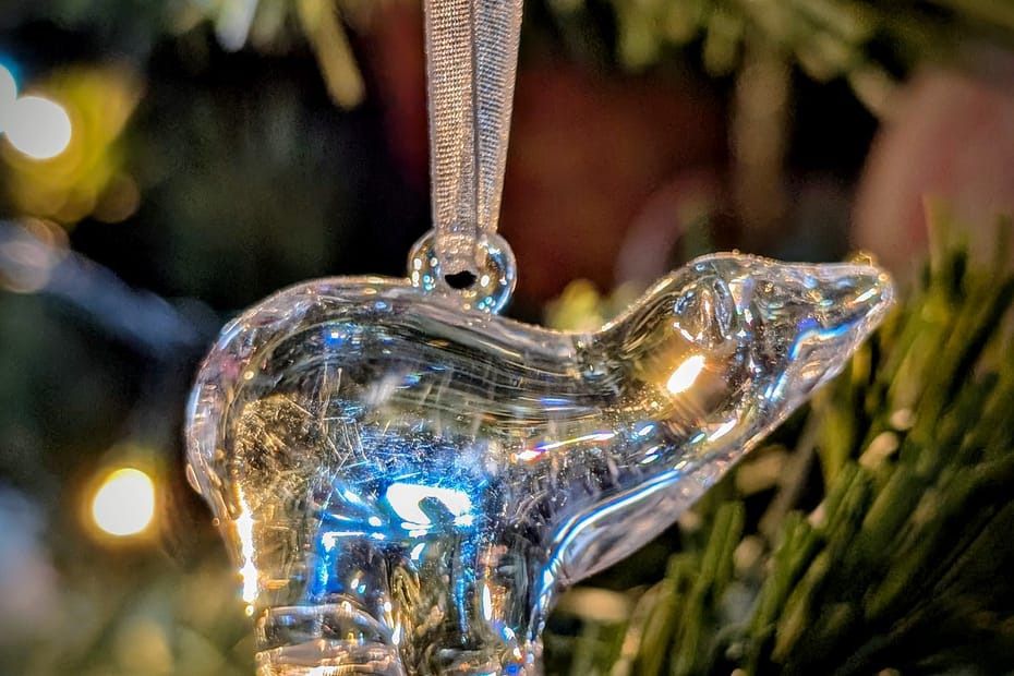 Glass polar bear Christmas ornament hanging on a tree, reflecting warm fairy lights, keeping calm at christmas with the little things